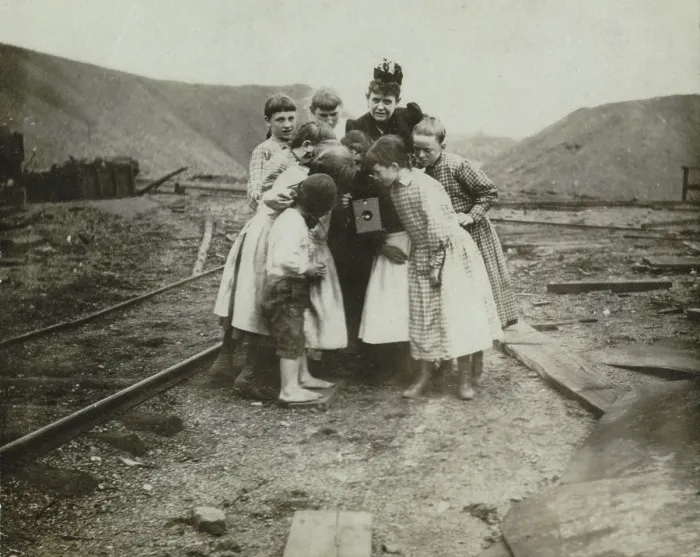 Framed Print : Photographer Frances Benjamin Johnston (back center), with group of children looking at her camera, titled: A Kodak creates a sensation, 1890-1910