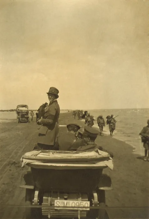 Framed Print : Photojournalist Helen Johns Kirtland in Europe after World War I. 1919. She photographs from an open car, riding on a beach with men in uniform as soldiers march past. Ca. 1919