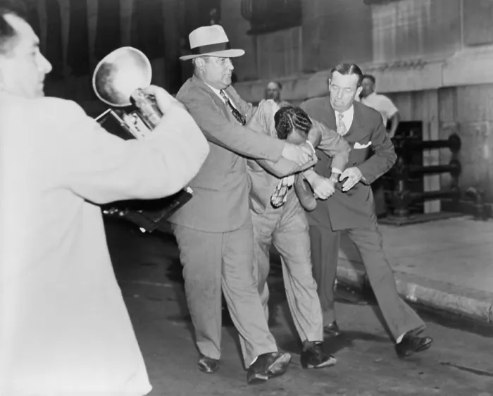 Framed Print : Two policemen forcibly escorting Vincent Jimmy Blue Eyes Ado (1904-2001), after appearing in lineup; a news photographer (left) foreground captures the scene