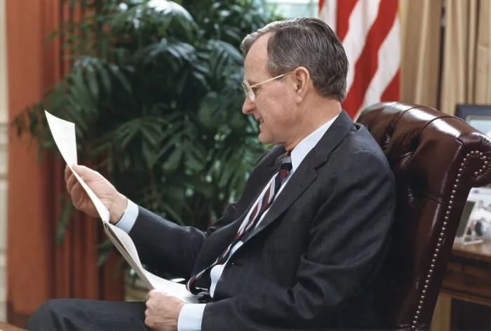Framed Print : President George H.W. Bush, reading a document at his desk in the White House, March 28, 1991 (BSLOC_2021_3_53)