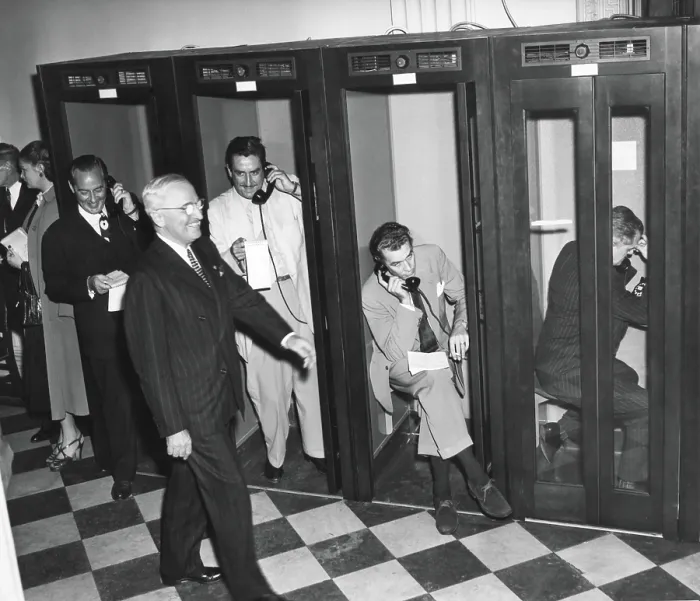 Framed Print : President Harry Truman walks past reporters in the telephone booths the Old State Department Building