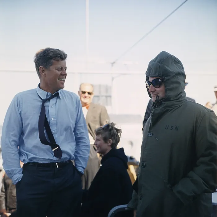 Framed Print : President Kennedy stands beside his bundled up Press Secretary, Pierre Salinger. They are watching the America's Cup Race from the Deck of the USS Joseph P. Kennedy, Jr