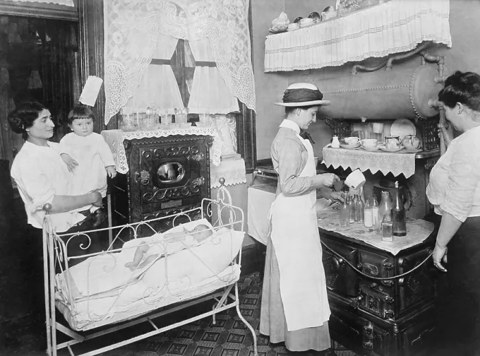 Framed Print : Public health nurse instructs a mother in the preparation of milk formulas for her baby. Nurses made house calls to reach into poor neighborhoods, June 1919 (BSLOC_2018_1_159)