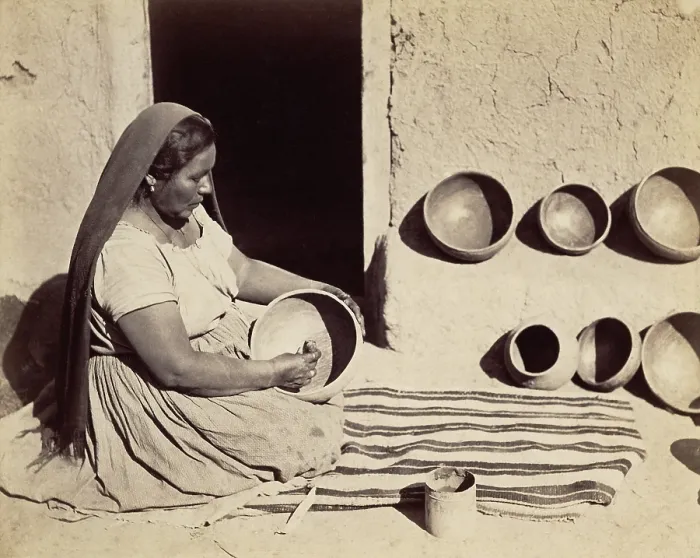 Framed Print : A Pueblo Indian woman polishes a pottery bowl in a doorway. 1879 photograph by John K. Hillers
