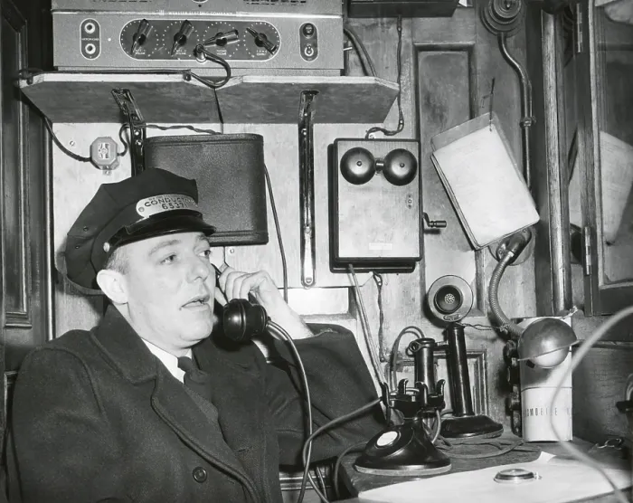 Framed Print : Railroad conductor uses an on board telephone to communicate with other parts of the train. Ca. 1930's - (BSLOC_2015_1_231)