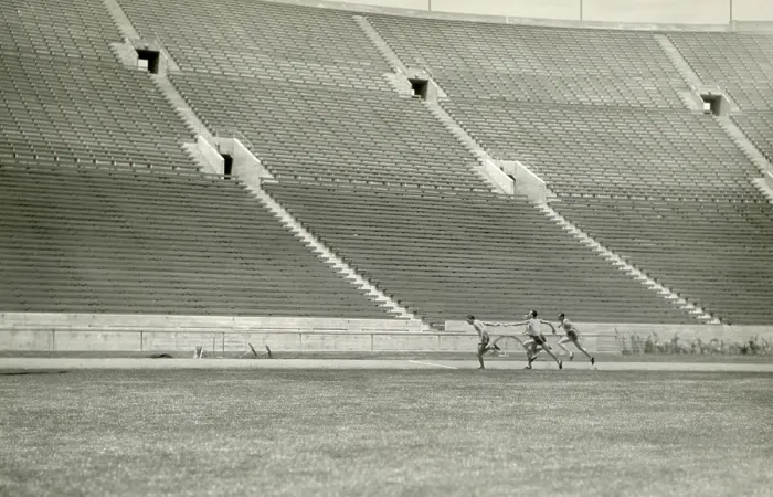Framed Print : Relay racers practice baton handoff in an empty stadium, c. 1920. Unknown location (BSLOC_2018_4_200)