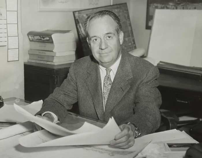 Framed Print : Robert Trent Jones, golf course architect, sitting at desk and holding drawings in 1953. - (BSLOC_2015_1_122)