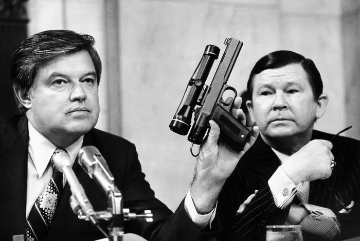 Framed Print : Senator Frank Church was chairman of the Senate Intelligence Committee. As John Tower looks on, he holds a CIA dart gun with a telescopic site