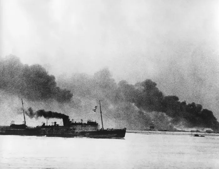 Framed Print : Ship leaving Dunkirk carrying defeated British and French soldiers to England. In the background the French port of Dunkirk burns under the German advance. World War 2