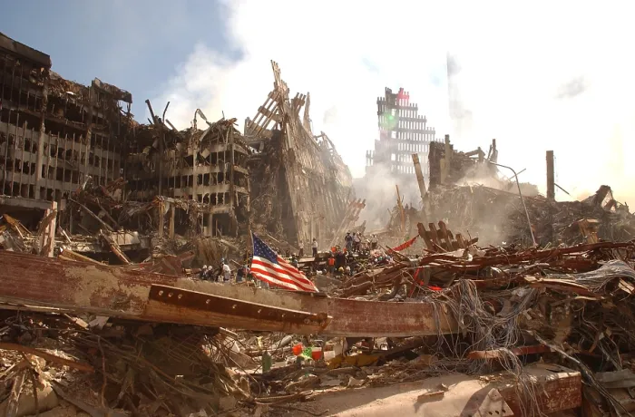 Framed Print : Smoke rises from the World Trade Center's collapsed North Tower. On the left are the remains of a lower structure, WTC 6. A large flag is secured to a beam in the foreground Framed Print : Smoke rises from the World Trade Center's collapsed North Tower. On the left are the remains of a lower structure, WTC 6. A large flag is secured to a beam in the foreground