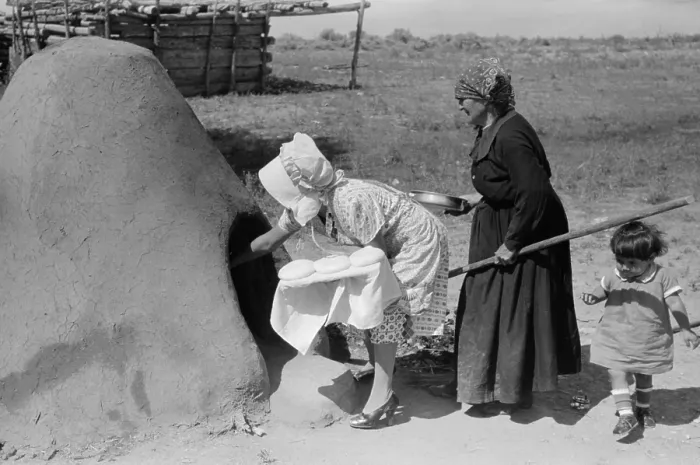 Framed Print : Two Spanish-American women placing loaves of bread in outdoor earthen oven for baking, Taos County, New Mexico