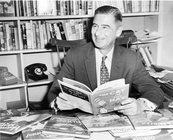 Framed Print : Ted Geisel (Dr. Seuss) (1904-1991) seated at desk covered with his uniquely humorous children's books. 1957