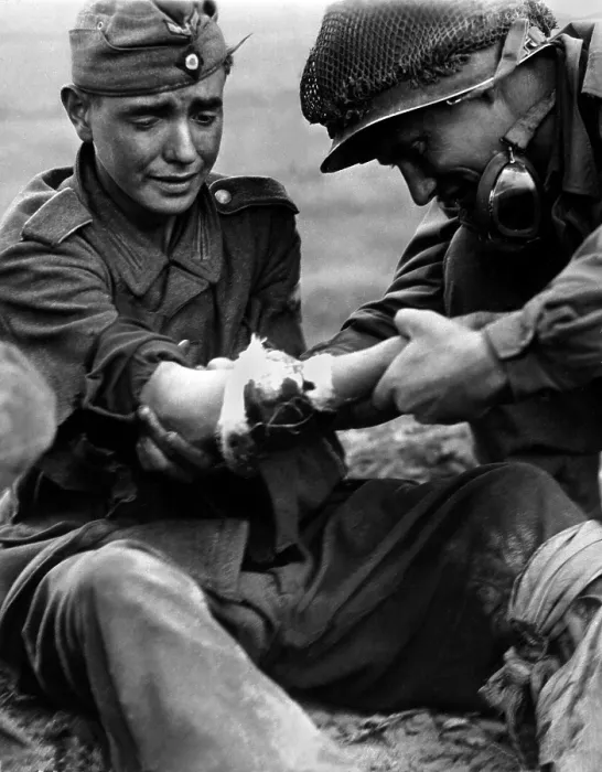 Framed Print : Teenage German POW's arm wound is examined by an older American soldier. In the last year of the World War 2, both Germany and U.S. lowered draft ages to fill ranks Framed Print : Teenage German POW's arm wound is examined by an older American soldier. In the last year of the World War 2, both Germany and U.S. lowered draft ages to fill ranks