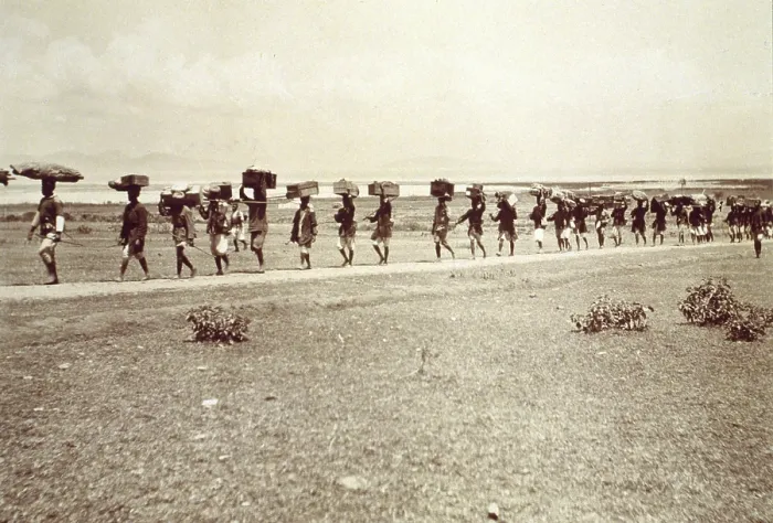Framed Print : Theodore Roosevelt's 1910 African safari on the march, with a line of African men on road, carrying trunks, boxes and other items