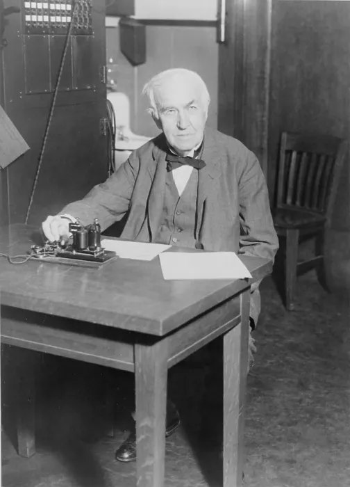 Framed Print : Thomas Edison, seated at desk, demonstrating an old telegraph transmitter in his West Orange, New Jersey, laboratory, 1930