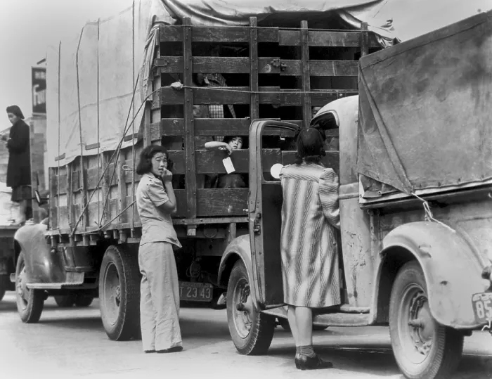 Framed Print : Trucks removing Japanese American and their luggage from Redondo Beach, California. Women hover near the trucks and a child can be seen looking out from the truck
