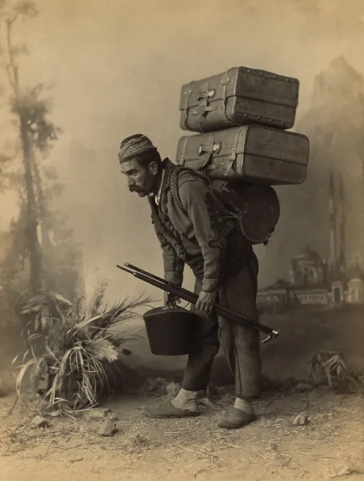 Framed Print : Turkish porter carrying luggage on his back. Studio portrait with painted backdrop of landscape with mosque, by Abdullah Freres, ca. 1890 Framed Print : Turkish porter carrying luggage on his back. Studio portrait with painted backdrop of landscape with mosque, by Abdullah Freres, ca. 1890