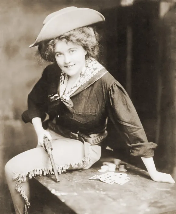 Framed Print : Turn of the century Cowgirl holding revolver, seated on a table, with playing cards and chips. Ca. 1900 Framed Print : Turn of the century Cowgirl holding revolver, seated on a table, with playing cards and chips. Ca. 1900