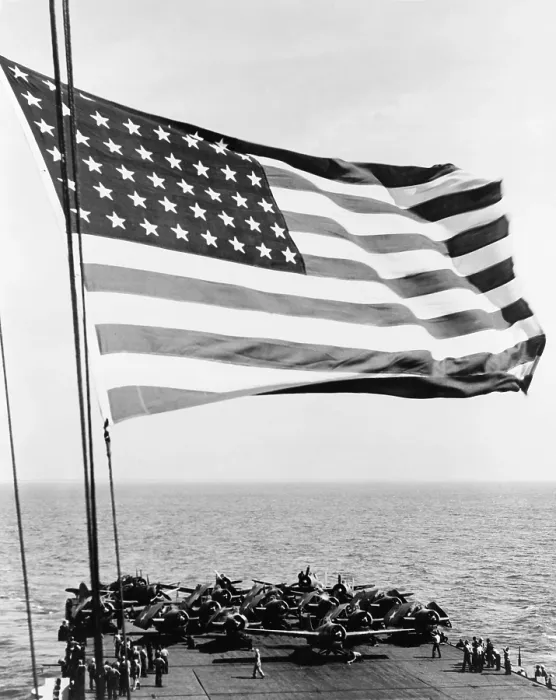 Framed Print : U.S. flag waving in foreground over flight deck of an escort carrier on July 16, 1943