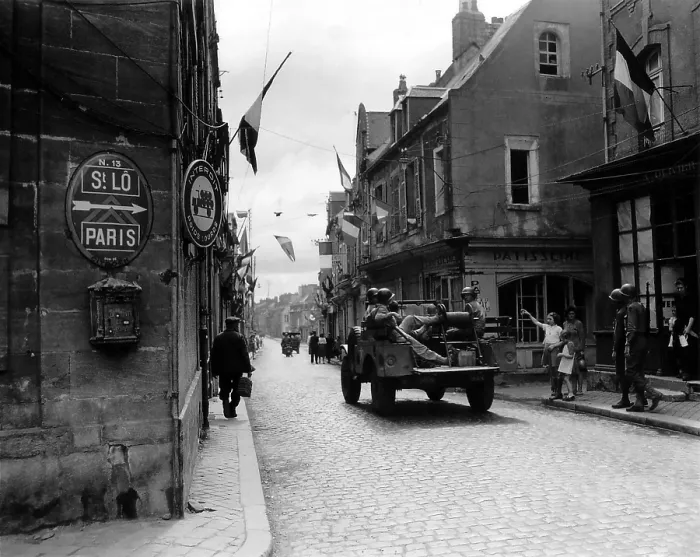 Framed Print : Five U.S. soldier ride through Carentan, France, on the road to Saint-Lo, June 12, 1944. French flags decorate the street of the newly liberated town