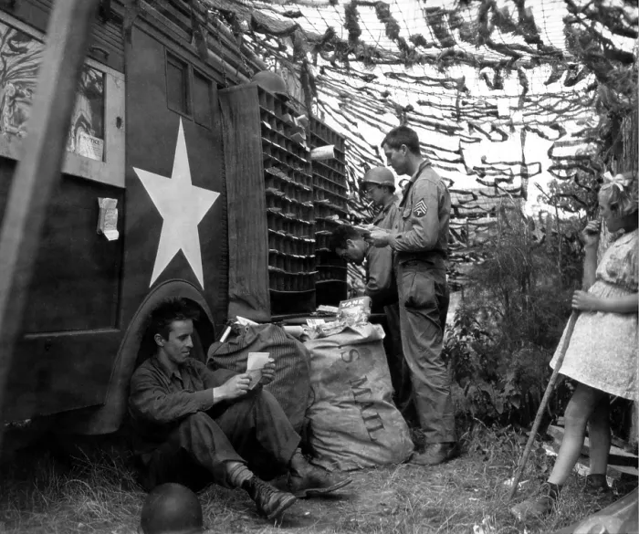 Framed Print : U.S. soldiers sorting mail under a camouflage net in Northern France. A young French girl observes the activity. June-Sept. 1944. World War 2. (BSLOC_2014_2_156)