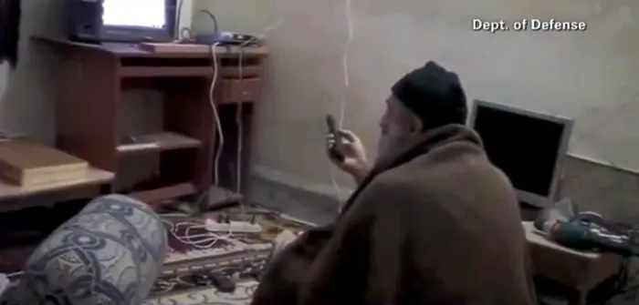 Framed Print : Video still of Al Qaeda Terrorist leader Osama Bin Laden with remote control in hand while viewing himself on television