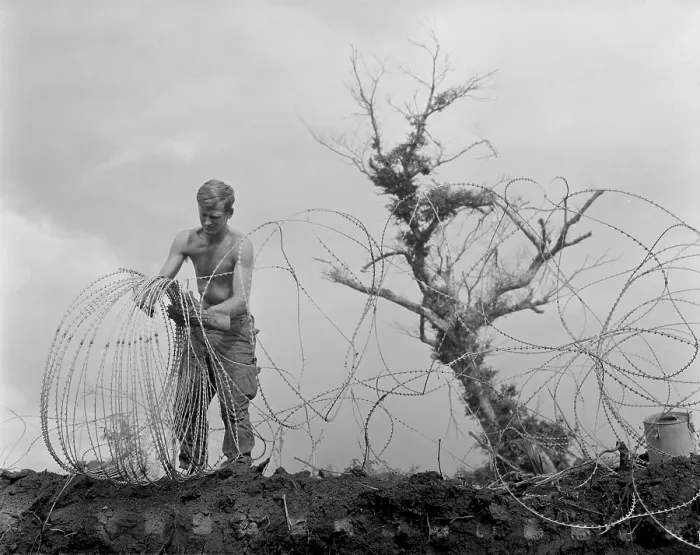 Framed Print : Vietnam War. A US Army infantryman takes down barbed tape surrounding the command post of Operation Utah Mesa