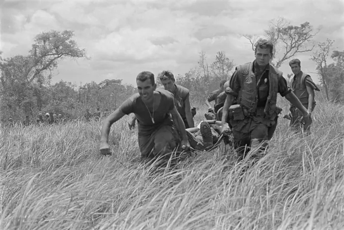 Framed Print : Vietnam War. While under heavy fire, US Marines are carry a wounded Marine to the evacuation helicopter near the Demilitarized Zone (DMZ) dividing North and South Vietnam