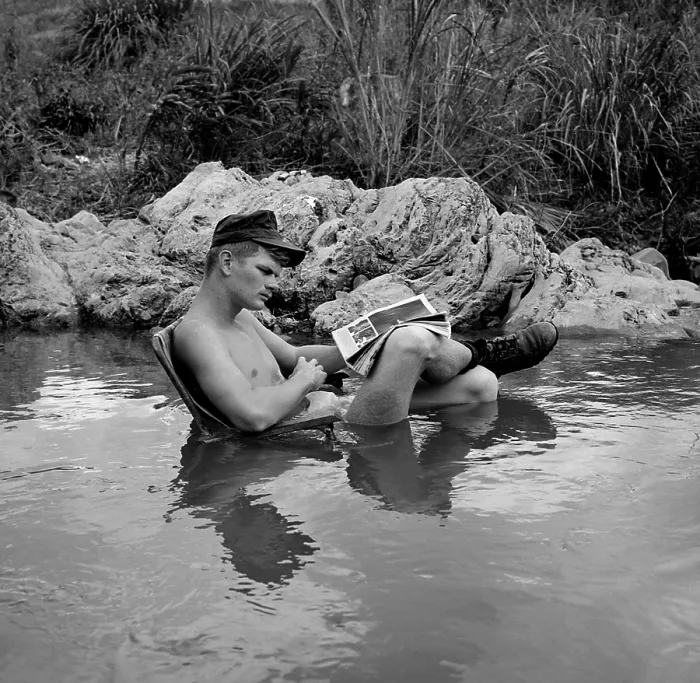 Framed Print : Vietnam War. US Marine rifleman takes time out to relax in a cool mountain stream, with an easy chair and his favorite magazine. 1968