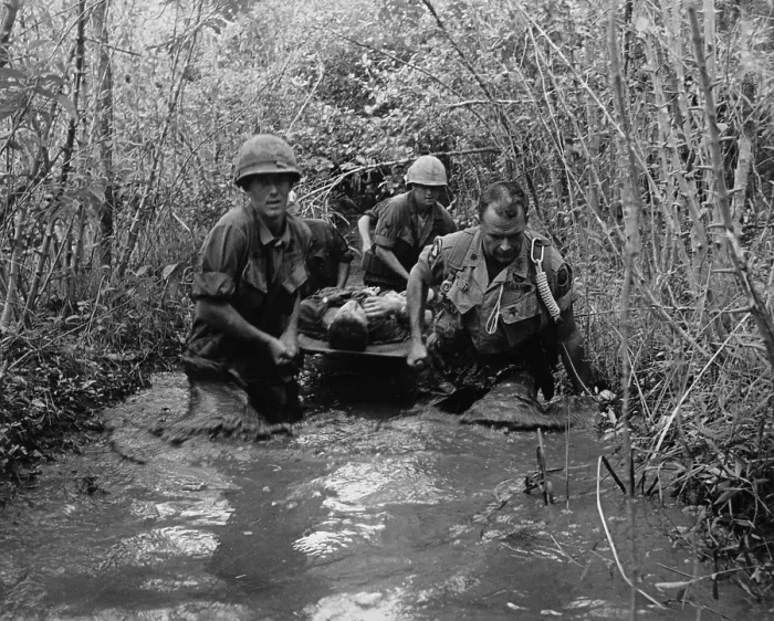 Framed Print : Vietnam War. US Soldiers carry a wounded comrade through a swampy area. 1969