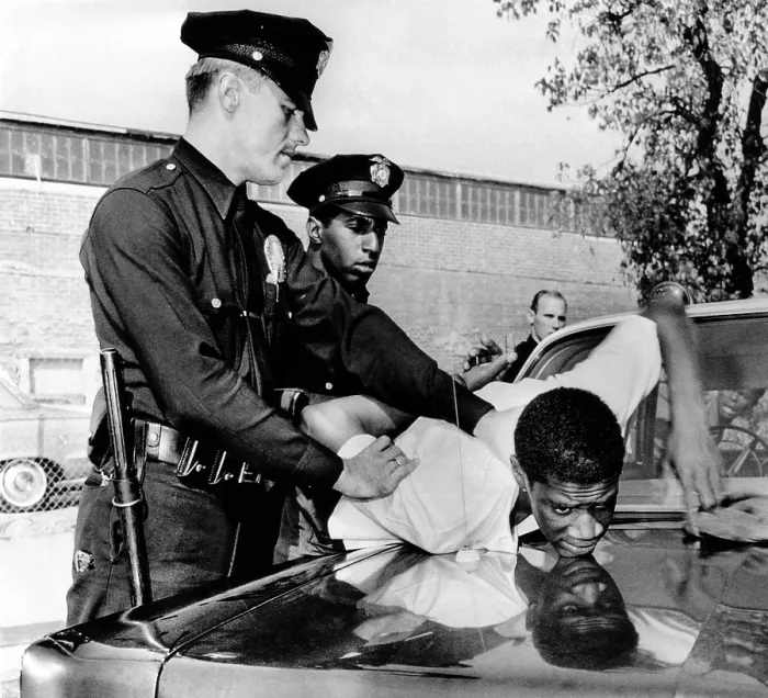 Framed Print : Violence in Los Angeles street. Police hold a African American teenager over the hood of a police car Framed Print : Violence in Los Angeles street. Police hold a African American teenager over the hood of a police car