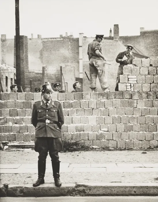 Framed Print : West Berlin policeman stands before the concrete block wall dividing East and West Berlin