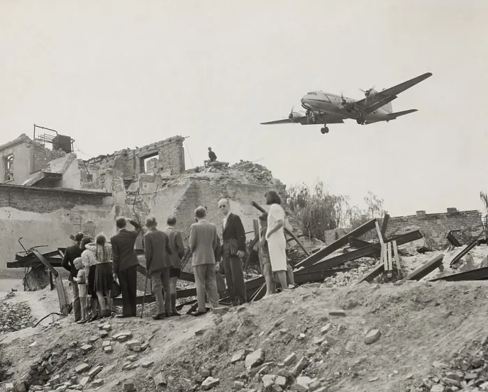 Framed Print : West Berliners gathered near war ruins in Berlin watch a U.S. Air Force transport plane