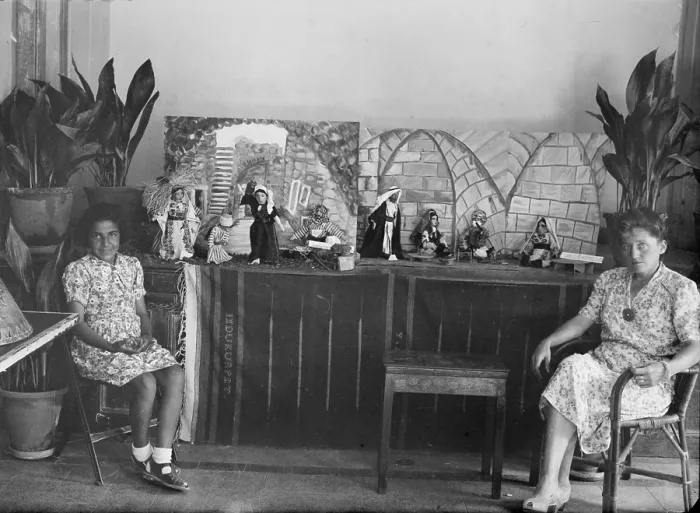 Framed Print : Woman and girl seated in front of dolls which are wearing traditional Arab dress, one group of dolls has label Dolls Ramallah, photograph, circa 1920-1946 Framed Print : Woman and girl seated in front of dolls which are wearing traditional Arab dress, one group of dolls has label Dolls Ramallah, photograph, circa 1920-1946