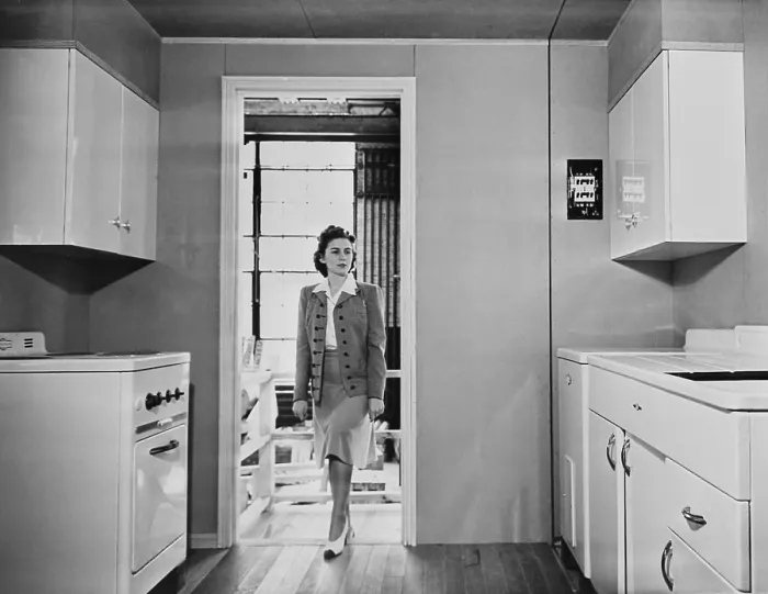 Framed Print : Women enters a modern 1940s kitchen with white enameled metal cabinets. The housing was built by the government for workers on TVA and other Defense projects in World War II