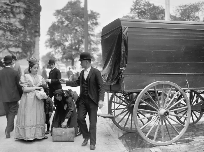Framed Print : Two women immigrants and a child engage a wagon for transport to their next stop, probably a boarding house or railroad station