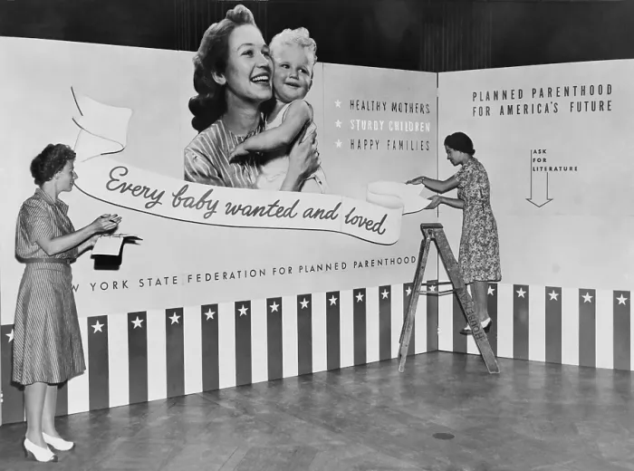 Framed Print : Two women working on panels for exhibit on planned parenthood featuring the slogan, Every baby wanted and loved