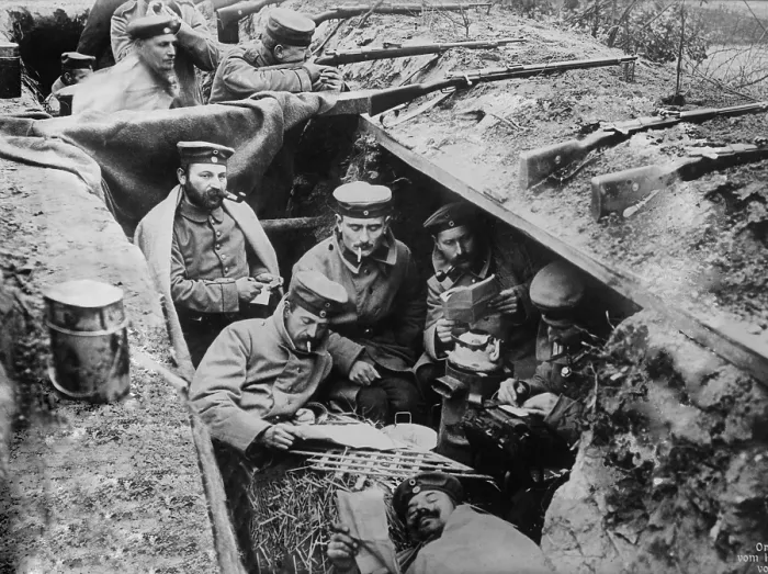 Framed Print : World War 1. German soldiers smoking, reading, and writing in their trench. In the background one soldier maintains a battle position. Western Front, ca. 1914-15