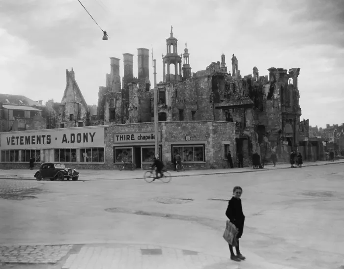 Framed Print : World War 2 destruction and Post war reconstruction in Caen, France. The ruins of homes and a church remain behind stores newly constructed from salvaged materials. 1946