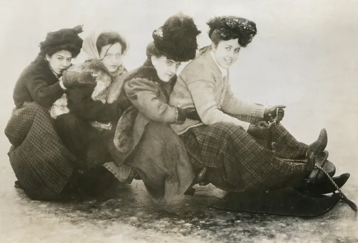 Framed Print : Four young American women on a sled, c. 1910. The huddled young girls wear layers of fur, wool, and leather winter clothing (BSLOC_2018_4_207)
