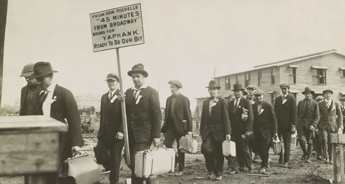 Framed Print : Young men in civilian clothes arriving for military service at Camp Upton, Long Island, NYS. One carries a sign: From New Rochelle, 45 minutes from Broadway, bound for Yaphank