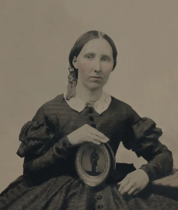 Framed Print : Young woman wearing mourning brooch and holding a framed image of unidentified soldier. Photo taken during the US Civil War, between 1861-1865 (BSLOC_2019_2_73)