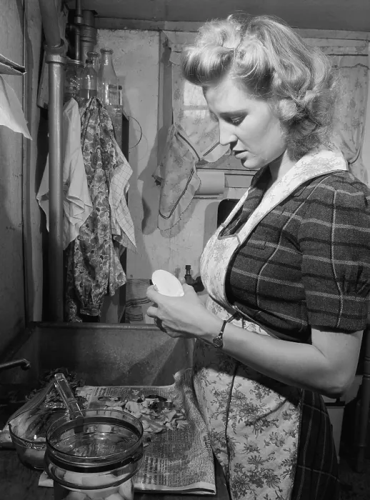 Framed Print : Young women peeling potatoes in her Washington D.C. apartment kitchen. She has a modern glass cooking pot and uses a newspaper to collect the potato peels for the garbage. Dec