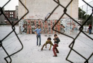 Ethnic Prints: 1970s America. Three young boys pose in front of a graffitied wall in a park in Brooklyn