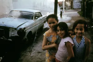 Ethnic Prints: 1970s America. Three young girls pose in front of an abandoned car in Brooklyn