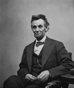 Lincoln Prints: Abraham Lincoln (1809-1865) seated and holding his spectacles and a pencil on Feb