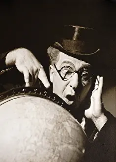 Globe Prints: Actor Ed Wynn poses behind a globe of earth with astonished expression