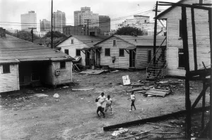 Housing Prints: African American children playing in slum in view of high rise buildings in background