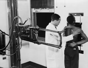 Tuberculosis Prints: African American doctor placing patient in the correct position for taking chest x-ray for use in the diagnosis in 1937