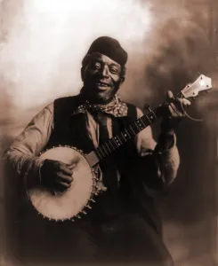 Folk Prints: African American man seated and holding banjo. Ca. 1911